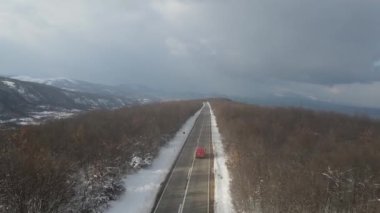 Seyahat yolculuğu ve tatil konsepti. Sırbistan 'ın Knjazevac kenti yakınlarında kış günü beyaz karla dağlık alanda giden otomobil üzerindeki yüksek açılı hava aracı videosu.