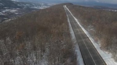 Seyahat yolculuğu ve tatil konsepti. Sırbistan 'ın Knjazevac kenti yakınlarında kış günü beyaz karla dağlık alanda giden otomobil üzerindeki yüksek açılı hava aracı videosu.