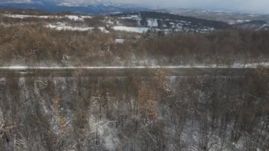 Seyahat yolculuğu ve tatil konsepti. Sırbistan 'ın Knjazevac kenti yakınlarında kış günü beyaz karla dağlık alanda giden otomobil üzerindeki yüksek açılı hava aracı videosu.