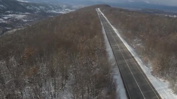 旅行の輸送と休暇のコンセプトセルビアのKnjazevac近くの冬の日に白い雪と山の範囲で運転する道路の車の高角度の空撮ドローンビデオ — ストック動画