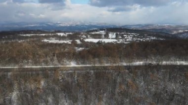 Seyahat yolculuğu ve tatil konsepti. Sırbistan 'ın Knjazevac kenti yakınlarında kış günü beyaz karla dağlık alanda giden otomobil üzerindeki yüksek açılı hava aracı videosu.