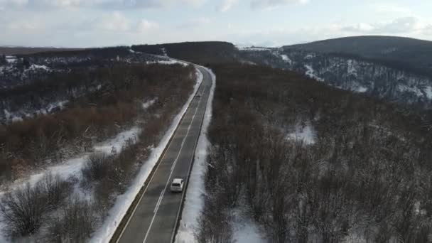 旅行の輸送と休暇のコンセプトセルビアのKnjazevac近くの冬の日に白い雪と山の範囲で運転する道路の車の高角度の空撮ドローンビデオ — ストック動画
