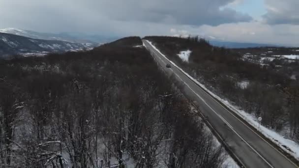 旅行の輸送と休暇のコンセプトセルビアのKnjazevac近くの冬の日に白い雪と山の範囲で運転する道路の車の高角度の空撮ドローンビデオ — ストック動画