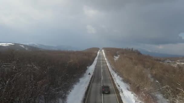 旅行の輸送と休暇のコンセプトセルビアのKnjazevac近くの冬の日に白い雪と山の範囲で運転する道路の車の高角度の空撮ドローンビデオ — ストック動画