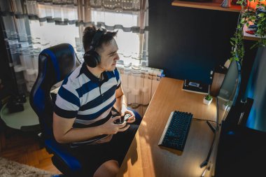 Kafkasyalı genç bir erkek bilgisayarında video oyunları oynuyor. Karanlıkta, kafasında kulaklıklarla tek başına monitöre bakıyor. Gerçek insanlar boşluğu kopyalıyor.