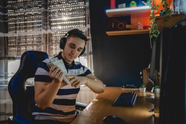 İnternet dersi sırasında bilgisayar başında karanlık bir odada oturup rehber ya da özel öğretmen olarak internetten eğitim alan beyaz bir genç adam gerçek insanlar.