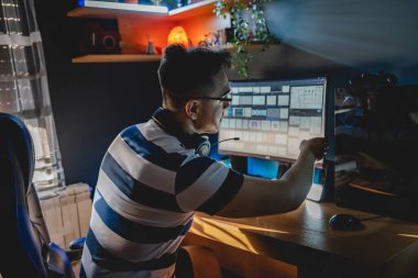 Yetişkin bir beyaz adamın evdeki bilgisayar masasında oturup ekrandaki ekrana bakarak kripto döviz kuru piyasasını ve madencilik yatırımlarını kontrol ettiğini gördüm.