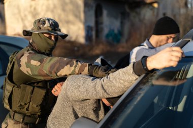 Kimliği belirsiz asker ya da özel kuvvetler polisinin güneşli bir günde suçluları, kaçak göçmenleri ya da teröristleri tutuklaması.