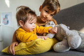 Kis kaukázusi fiú öt éves feküdt az ágyon az öccsével vagy húgával játszik fényes szobában igazi emberek családi kötelék testvérek testvér és nővér