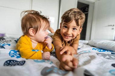 Küçük beyaz bir çocuk, 5 yaşında, yatağında erkek ya da kız kardeşiyle yatıyor. Kameraya bakıyor. Gerçek insanlar, aile bağı kuran kardeşler.