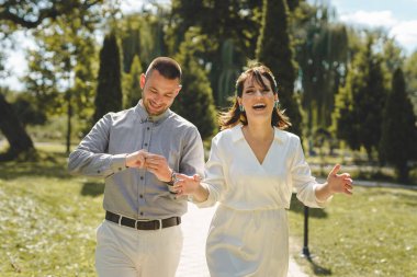Mutlu gelin ve damat evlendiler. Evlilik ve aşkı kutluyorlar. Güneşli bir günde parkta yürüyorlar.