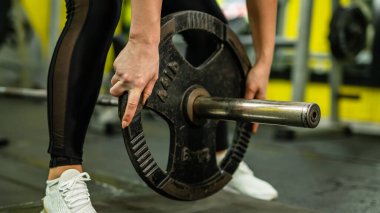 Spor salonunda vücut geliştirme ve ağırlık kaldırma konsepti fotokopisi çekerken beyaz kadın bir sporcunun ellerine yakın çekim yapın.