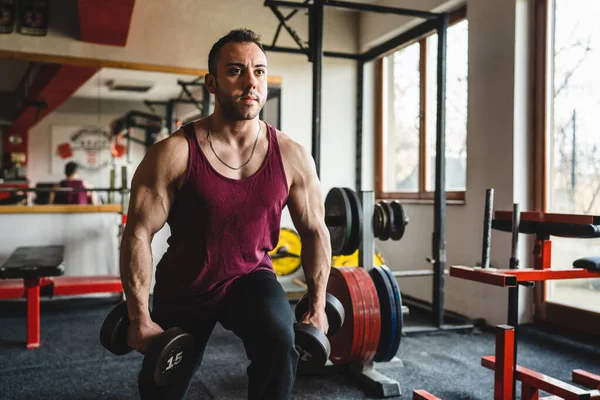 One man male bodybuilder training legs at the gym using dumbbells while doing lunges exercise real people copy space