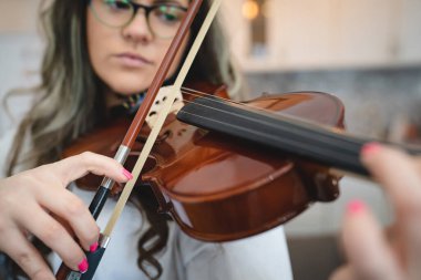 Bir kadın, elinde keman tutan yetişkin beyaz kadın portresi müzik çalmayı ve pratik yapmayı öğreniyor. Gerçek insanlar, seçici bir şekilde enstrüman ve ele odaklanıyor.