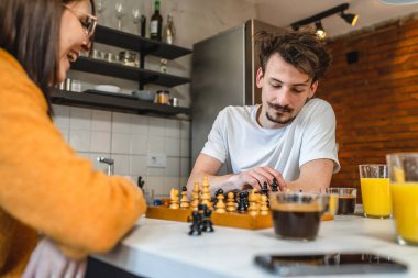 İki kişi genç adam ve kadın karı koca mutfak masasında satranç oynuyorlar sabah rutin eğlence aktivitesi çifti ilişki içinde gerçek insanları taklit etmeyi öğreniyorlar.