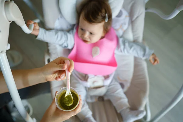 Fütterung Kleiner Kaukasischer Babys Mit Silikon Lätzchen Mit Brokkoli Gemüsepüree — Stockfoto
