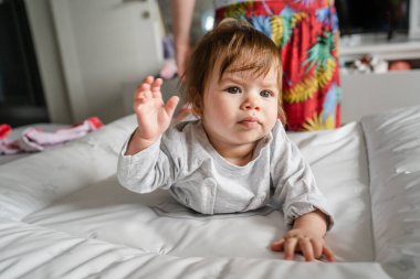 Beyaz bebek, evinde, aydınlık odada, göbeğinin üstünde yatarken annesi de arkasında dikilip gerçek insanların çocukluk ve aile kavramlarını değiştirecek kıyafetler arıyor.