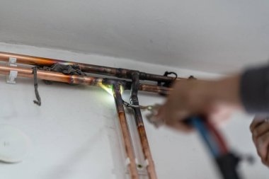 Bilinmeyen sanayi işçisi tesisatçı. Merkezi ısıtma bakır boruları olan, evin duvarında meşale ya da kaynak makinesi kullanan, iş yerindeki gerçek insanlar.