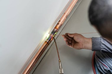 Bilinmeyen sanayi işçisi tesisatçı. Merkezi ısıtma bakır boruları olan, evin duvarında meşale ya da kaynak makinesi kullanan, iş yerindeki gerçek insanlar.