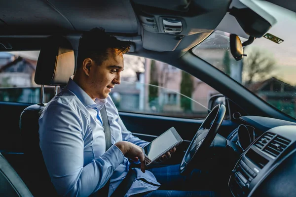 自動車で待っている間 デジタルタブレットを使用して車の前の席に座って道路の方向を確認したり ビジネスの詳細を注文する一人の若い大人のマネージャーや営業部長ビジネス人 — ストック写真
