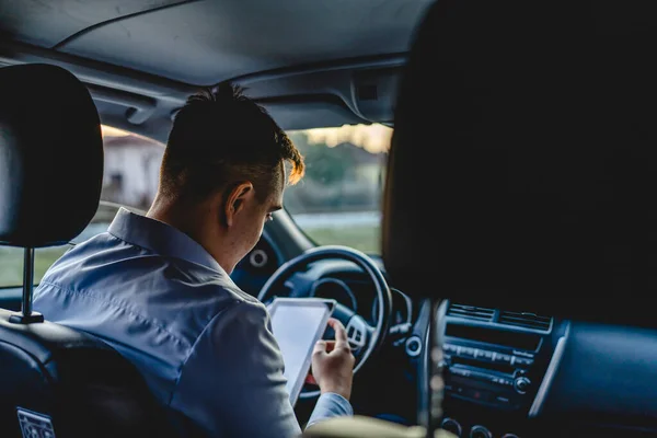 감독자는 자동차 안에서 기다리는 디지털 태블릿을 사용하여 자동차 앞자리에 방향을 — 스톡 사진