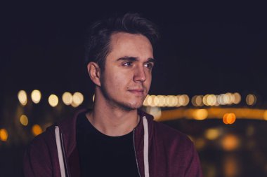 Genç bir beyaz adamın portresi şehrin veya kasabanın dışında dikilmiş fotokopi odasına bakıyor.