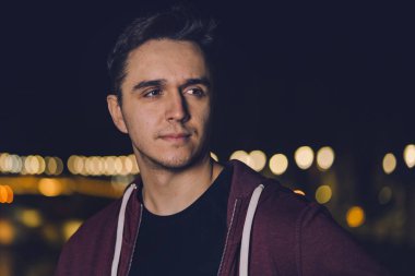 Genç bir beyaz adamın portresi şehrin veya kasabanın dışında dikilmiş fotokopi odasına bakıyor.