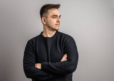 25 yaşında beyaz bir adamın portresi. Kısa saçlı, beyaz arka planda kameraya bakıyor. Süveter fotokopi alanı giydiğini düşünüyor.