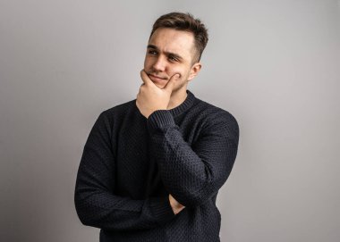 25 yaşında beyaz bir adamın portresi. Kısa saçlı, beyaz duvarın önüne bakıyor. Süveter fotokopi alanı giydiğini düşünüyor.