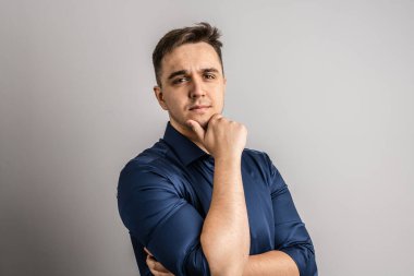 25 yaşında beyaz bir adamın portresi. Kısa saçlı, beyaz arka planda kameraya bakıyor. Gömlek fotokopi odası giydiğini düşünüyor.