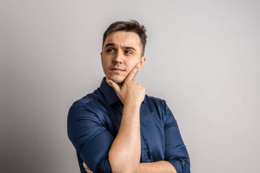 25 yaşında beyaz bir adamın portresi. Kısa saçlı, beyaz duvarın önüne bakıyor. Süveter fotokopi alanı giydiğini düşünüyor.