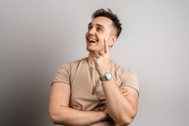 Yetişkin beyaz bir adamın portresi. 25 yaşında. Arka planda beyaz bir duvarın önünde kameraya bakıyor.