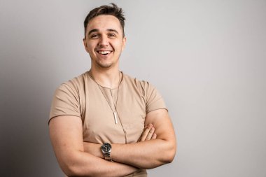 Yetişkin beyaz bir adamın portresi. 25 yaşında. Arka planda beyaz bir duvarın önünde kameraya bakıyor.