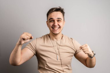 Kafkasyalı mutlu bir erkek stüdyonun ön görüntüsünü çekti başarıyı kutladı, olumlu duygular ve jest gülümsemesi güçlü bir şekilde kameranın kaslarına baktı.