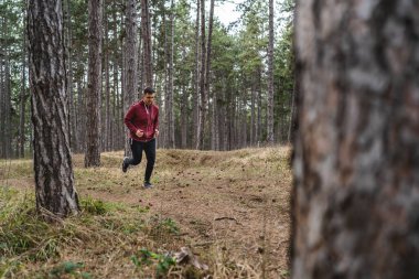 Yandan bakıldığında, genç beyaz bir erkek sonbahar ya da bahar günlerinde ormanda koşuyor. Spor fitness ve eğlence anlayışı. Gerçek insanlar uzayı taklit eder.