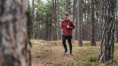 Yandan bakıldığında, genç beyaz bir erkek sonbahar ya da bahar günlerinde ormanda koşuyor. Spor fitness ve eğlence anlayışı. Gerçek insanlar uzayı taklit eder.