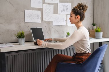 Genç beyaz bir kadın ofis masasında oturmuş laptopta çalışırken dinlenen belgeleri inceliyor gerçek insanlar uzay mühendisi kadın projesini kopyalıyor.