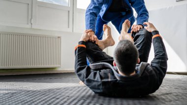 İki Brezilyalı jiu jitsu BJJ sporcusu akademi dövüş sanatları sahasında antrenman yapıyor kimono gi spor üniforması giyiyorlar spor minderlerinde spor jiujitsu ve kendini savunma konsepti fotokopi uzayı