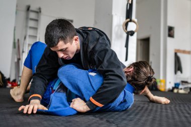 İki Brezilyalı jiu jitsu BJJ sporcusu akademi dövüş sanatları sahasında antrenman yapıyor kimono gi spor üniforması giyiyorlar spor minderlerinde spor jiujitsu ve kendini savunma konsepti fotokopi uzayı