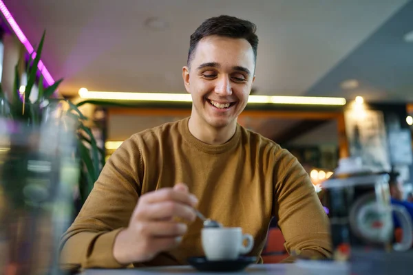 若いですCaucasian男座っているだけでカフェフロントビューの1幸せな男性ホールディングのコーヒーコピースペースのカップ — ストック写真