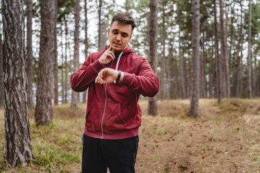 Genç bir adam nabzını kontrol ediyor. Ormanda antrenman yaparken kalp atışları hızlanıyor. Gerçek insanlar uzayı taklit ediyor.