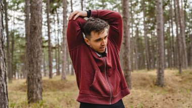 Ormanda ya da halk parkında esneyen tek bir adam. Genç, beyaz bir erkek. Açık hava eğitimine hazırlanıyor.