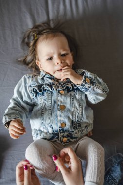 Beyaz bir kızın evde ceketle yattığı beyaz bir bebeğin portresi.