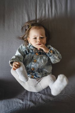 Beyaz küçük bir kızın üst görünüm portresi. Evdeki yatakta yatıyordu. Ceketi uzundu.