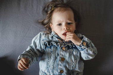 Beyaz bir kızın evde ceketle yattığı beyaz bir bebeğin portresi.