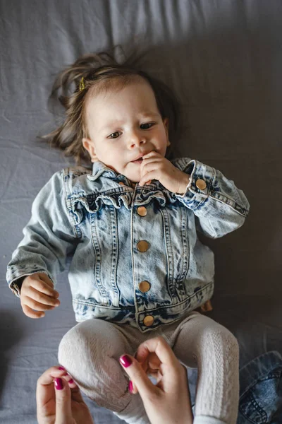 Beyaz bir kızın evde ceketle yattığı beyaz bir bebeğin portresi.