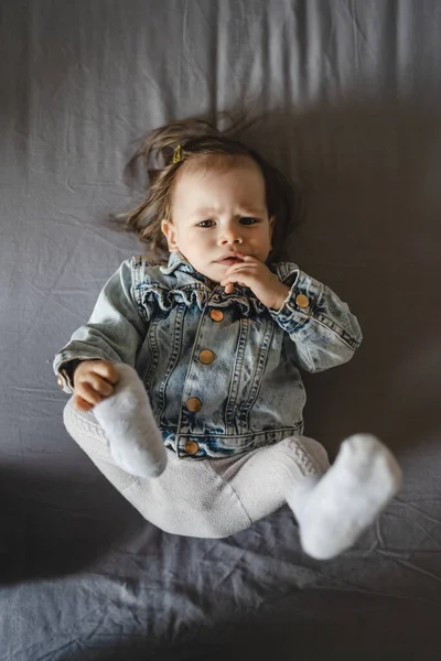 Beyaz küçük bir kızın üst görünüm portresi. Evdeki yatakta yatıyordu. Ceketi uzundu.