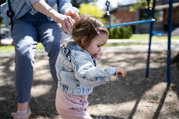 明るい春の日に歩くのを助けながら 彼女の母親が手を握って公園で一人の小さな白人の子供の女の子子供の頃の開発学習と家族の概念コピースペース — ストック写真