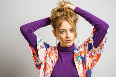 Sarışın, güzel bir kadın beyaz arka plan önünde fotoğraf çekmiş. Fotokopi çektirirken doğal olarak 20 yaşındaki saçlarını düzelten kameraya bakıyor.