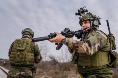 Savaş köpeklerinden iki asker paralı asker üniformalı silahlı adamlar savaş alanında çatışma bölgesinde demiryolunu emniyete alırken görev sırasında devriye bölgesini gözlüyor.